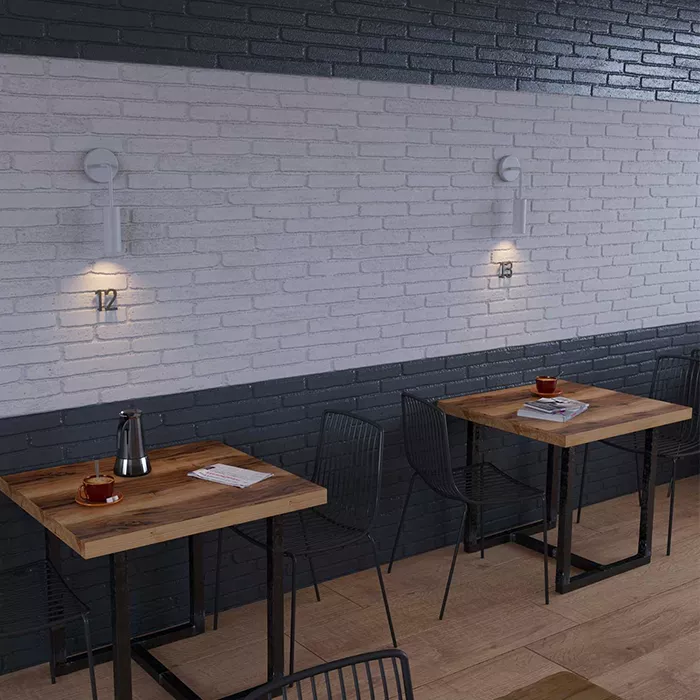 Darc — Deux tables en bois avec chaises métalliques noires devant un mur en briques claires, éclairées par deux appliques murales industrielles numéro