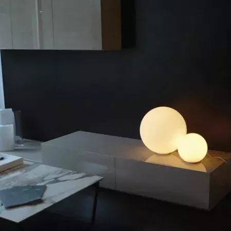 Darc — Deux luminaires sphériques blancs posés sur une console basse, diffusant une lumière douce et chaude dans un intérieur épuré avec des meubles s