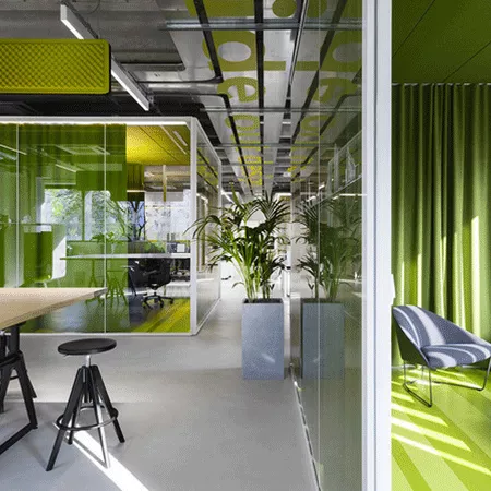 Darc — Un espace de coworking lumineux avec des murs végétalisés en vert, des plantes d'intérieur, des tables basses et des chaises design, éclairé pa