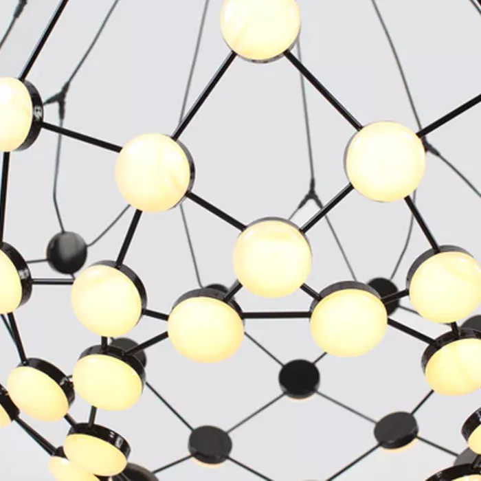 Darc — Un plafond lumineux suspendu en métal noir avec une structure géométrique complexe, composé de multiples ampoules rondes et dorées éclairées, c