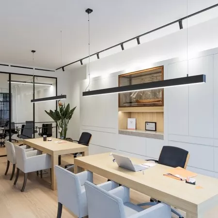 Darc — Une salle de réunion spacieuse et lumineuse équipée de deux grandes tables en bois clair entourées de chaises ergonomiques. Des éclairages susp