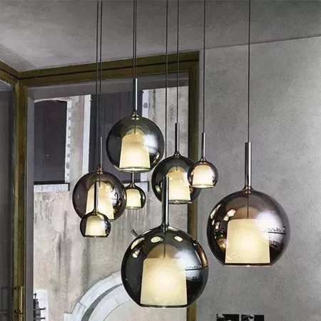 Darc — Ensemble de six suspensions sphériques en métal brillant suspendues à différentes hauteurs, diffusant une lumière douce et chaude dans un intér