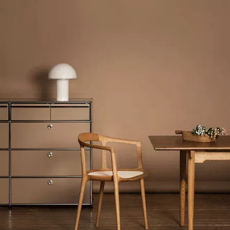 Darc — Une chaise en bois clair à dossier droit et assises blanches, posée devant une table ronde en bois massif avec un plateau en verre et des boule
