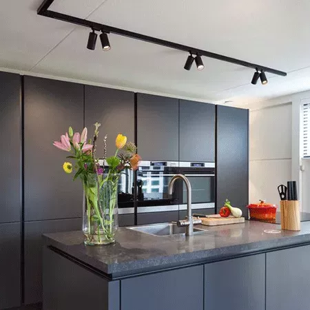 Darc — Une cuisine contemporaine avec des meubles de couleur anthracite, un plan de travail en pierre noire, des éclairages encastrés au plafond, un é