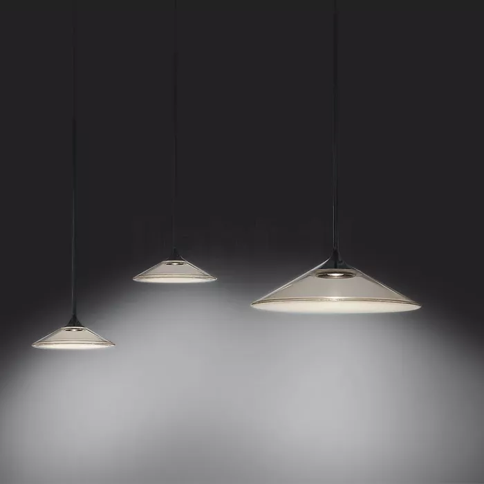 Darc — Trois suspensions lumineuses en forme de cône aplati, suspendues par des câbles noirs, éclairant une surface grise avec une lumière douce et di