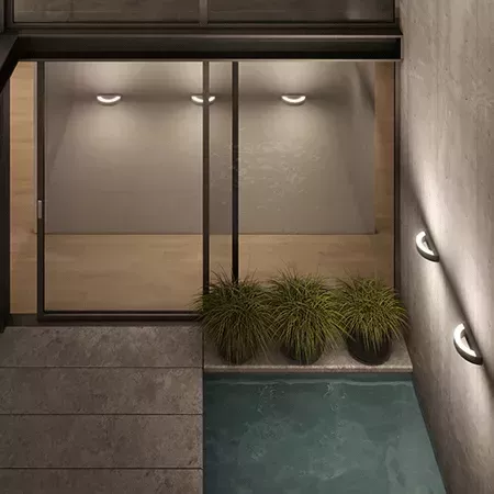 Darc — Une salle de bain moderne avec une douche à l'italienne sans rebord, éclairée par des spots intégrés dans le mur en béton. À droite, une petite