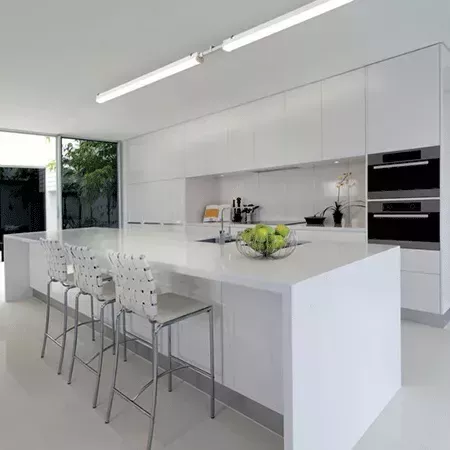Darc — Une cuisine contemporaine dotée d’un grand îlot central en marbre blanc, équipé d’un plan de travail lisse et de deux bar stools en métal avec