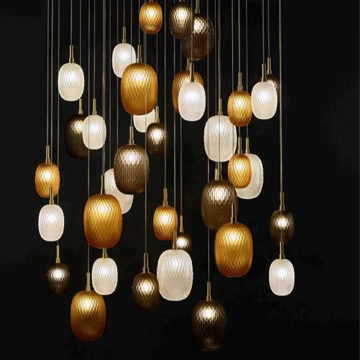 Darc — Une suspension lumineuse composée de multiples ampoules en forme d'œufs aux teintes dorées, brunes et blanches, suspendues à différentes hauteu