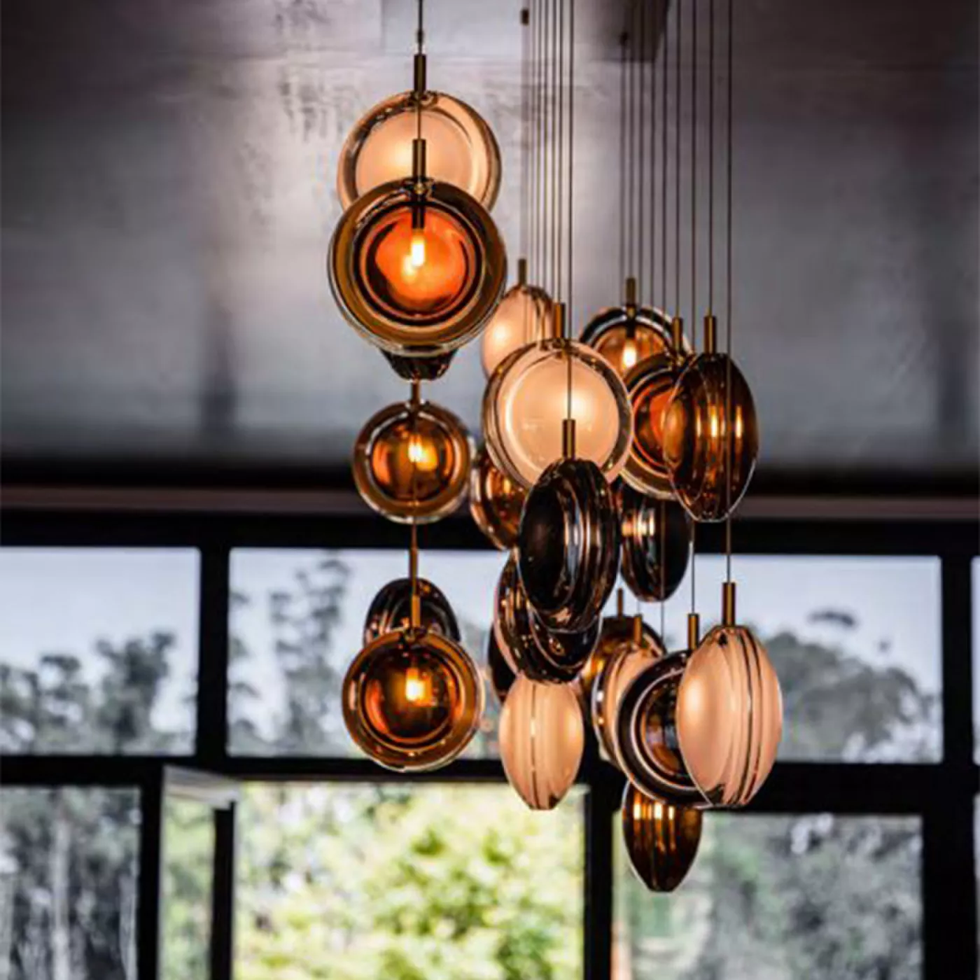 Darc — Un ensemble de luminaires suspendus en forme de sphères dorées et noires, accrochés en grappe au plafond, diffusant une lumière chaude et tamis