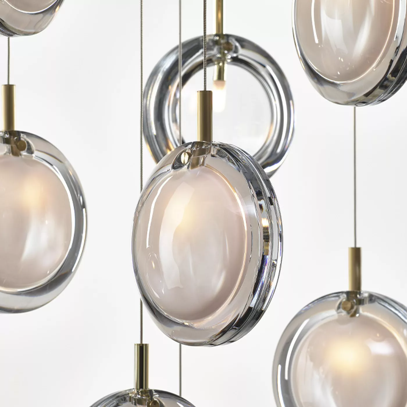 Darc — Ensemble de luminaires suspendus en forme de sphères transparentes avec des fixations dorées, diffusant une lumière douce et homogène, idéal po