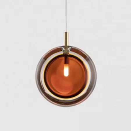 Darc — Une applique suspendue composée de deux sphères concentriques en métal doré et verre teinté ambre, éclairée par une ampoule centrale diffusant