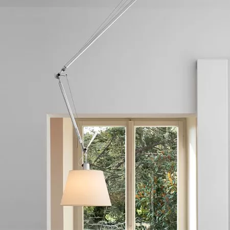 Darc — Une applique murale design suspendue par un bras articulé au-dessus d'une fenêtre ouverte, éclairant une pièce avec une lumière douce et mettan