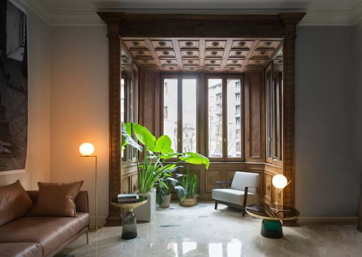 Darc — Un salon élégant éclairé par deux lampes design posées sur des tables basses. Un grand canapé en cuir et un fauteuil blanc sont disposés autour