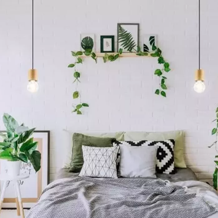 Darc — Une chambre épurée avec un lit bien fait, des coussins géométriques et des couvertures grises. Au-dessus, une étagère en bois avec des cadres n