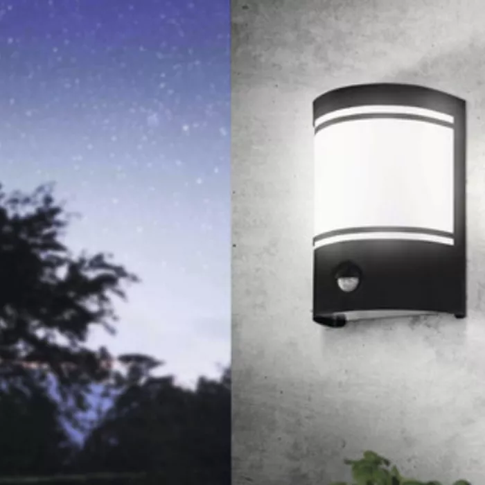 Darc — Un projecteur mural moderne allumé sur un mur gris clair, avec une lumière blanche intense et un capteur intégré, sous un ciel nocturne étoilé