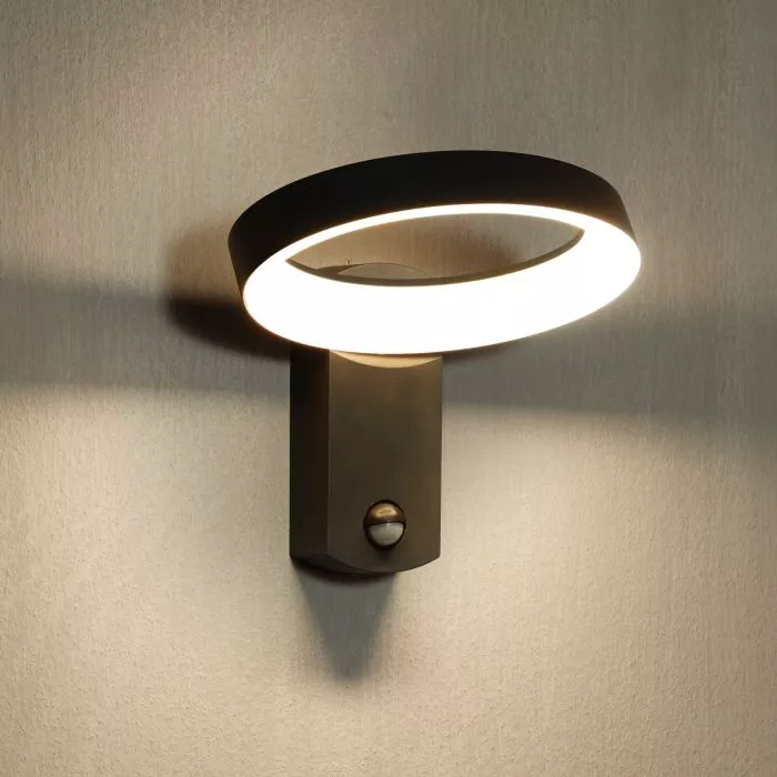 Darc — Applique murale design fixée au mur, composée d’un large cercle lumineux blanc diffusant une lumière douce et uniforme, montée sur un socle noi