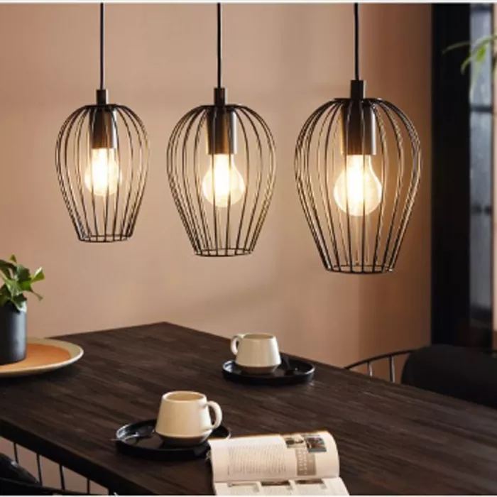 Darc — Trois appliques murales en métal suspendues au-dessus d'une table en bois sombre, éclairant une ambiance chaleureuse avec des ampoules visibles