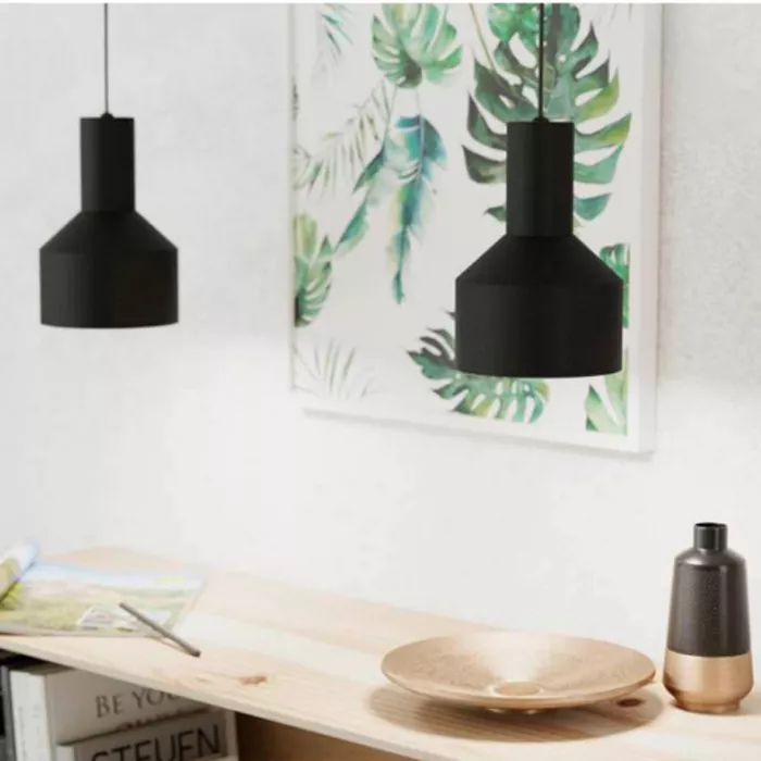 Darc — Deux lampes suspendues noires en forme de cône placées au-dessus d’un bureau en bois clair. À droite, un vase noir et doré et une assiette en b