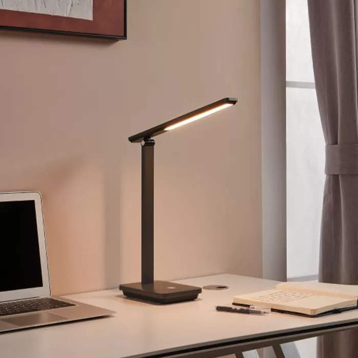 Darc — Une lampe de bureau design à bras articulé et lumière LED blanche, posée sur un bureau près d'un ordinateur portable et d'un carnet, avec une f