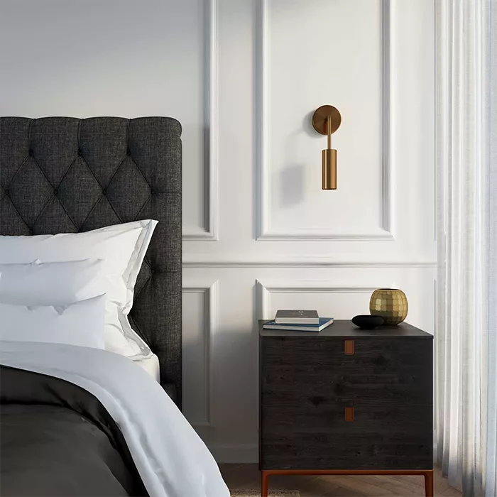 Darc — Une chambre sobre avec une tête de lit en tissu gris foncé à motifs géométriques, une applique murale circulaire en métal doré fixée près du li