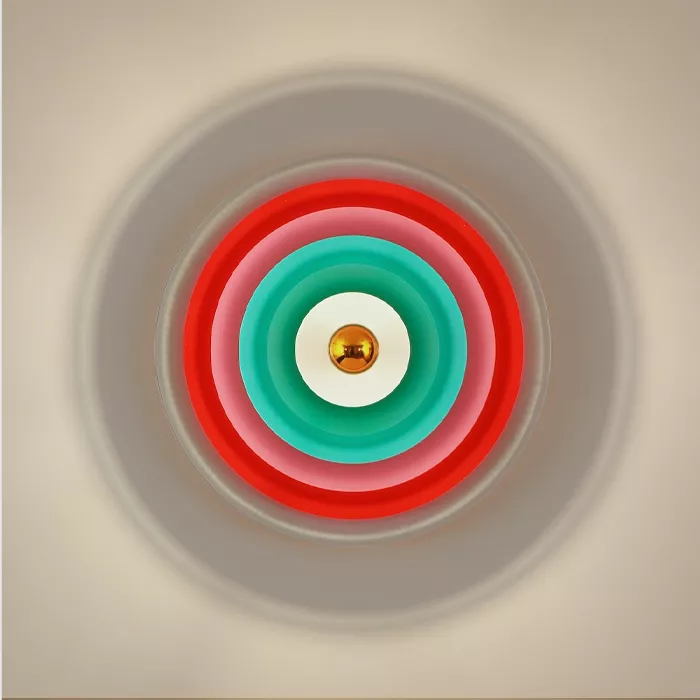 Darc — Un éclairage mural circulaire composé de trois cercles concentriques aux couleurs turquoise, rouge et gris clair, avec un centre doré brillant