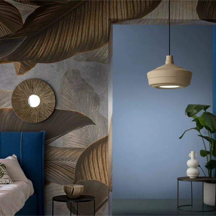 Darc — Une chambre avec un luminaire suspendu en forme organique beige, un lit bleu nuit, un mur décoré de motifs de feuilles en relief dorées et une