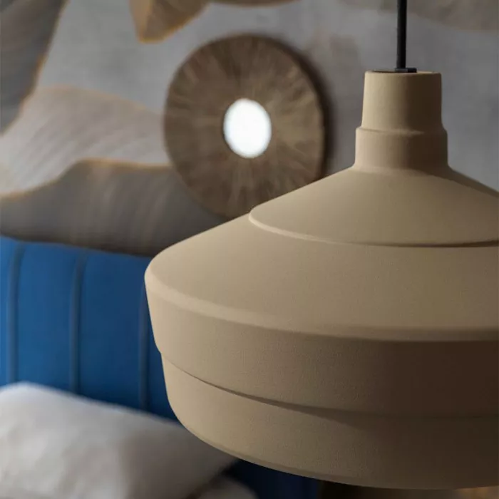 Darc — Une applique murale en céramique beige, de forme organique et légèrement striée, suspendue près d’un miroir rond à bord doré, dans un intérieur