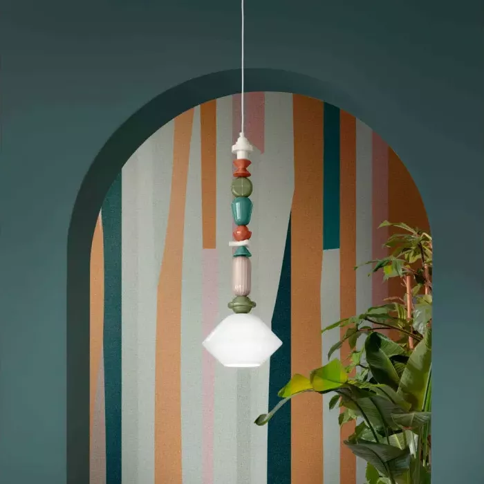 Darc — Une applique murale suspendue sous une arche peinte en dégradés de bleu, orange et vert, éclairée par une ampoule blanche. Elle est ornée d’un
