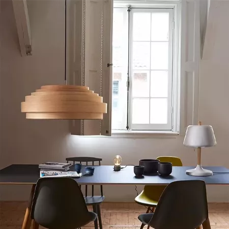 Darc — Un luminaire suspendu en forme de disques empilés en bois clair éclaire une table basse rectangulaire près d'une fenêtre. La table est équipée