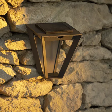 Darc — Applique murale solaire en métal noir fixée sur un mur en pierre apparente, avec un design géométrique et une lumière douce émanant de sa surfa