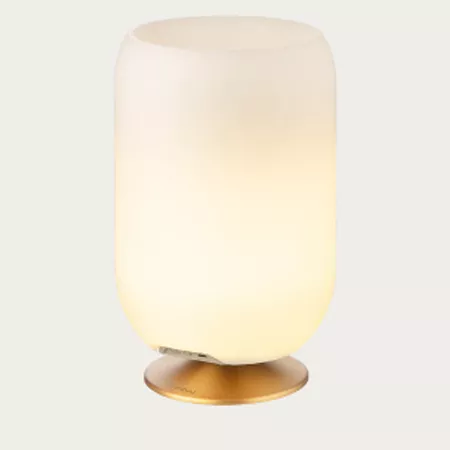 Darc — Lampe design sur pied en verre teinté diffusant une lumière chaude et douce, posée sur une base circulaire dorée.