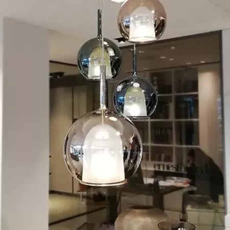 Darc — Quatre suspensions lumineuses en forme de sphères transparentes et métallisées, suspendues à différentes hauteurs dans un espace intérieur élég