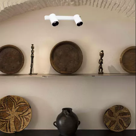 Darc — Une étagère murale blanche expose deux statuettes en bois sculpté, deux grands bols en terre cuite et deux paniers tissés géométriques. Une lam