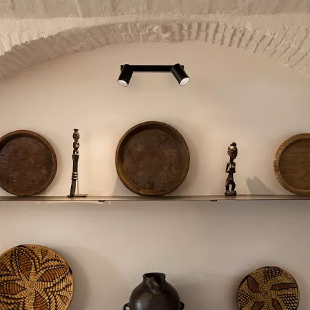 Darc — Une étagère fixée sous une voûte blanche expose cinq objets : deux grands bols en terre cuite, deux figurines humaines stylisées en bois, un va