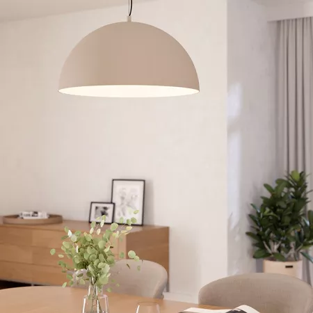 Darc — Une applique suspendue en forme de demi-sphère beige éclaire un salon épuré avec une table en bois clair, un vase avec des feuilles vertes et u