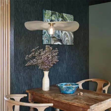 Darc — Un salon élégant avec une table en bois brut au centre, un vase contenant une branche séchée, une suspension lumineuse en forme d'aile au-dessu