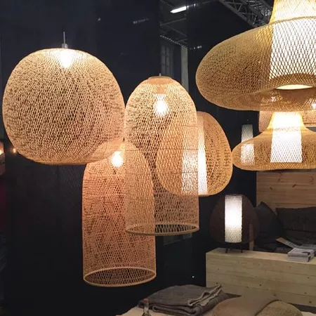 Darc — Quatre suspensions lumineuses en forme d’ovale, tissées en rotin clair, diffusant une lumière douce dans un espace design aux murs sombres et a