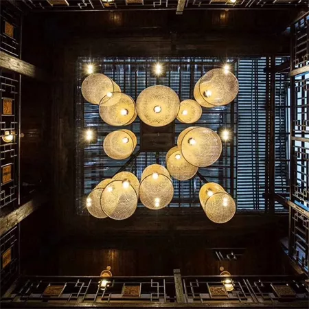 Darc — Ensemble de luminaires en forme de sphères tissées suspendus au plafond dans une pièce aux étagères en bois remplies de livres, créant une ambi