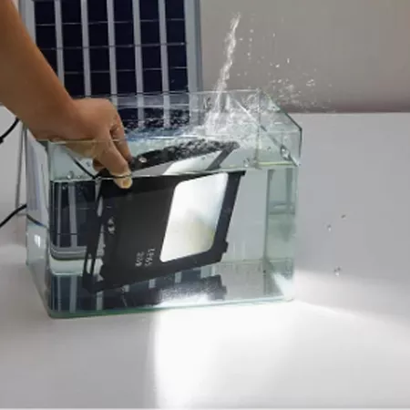 Darc — Une main verse de l’eau sur un clavier noir partiellement immergé dans un bac transparent en plastique, créant des éclaboussures autour de l’ap
