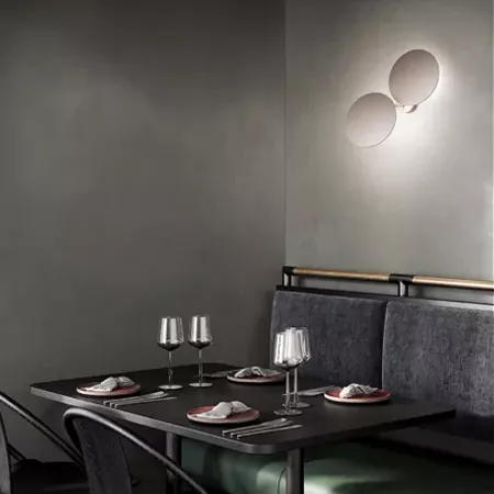 Darc — Une table noire rectangulaire dressée avec deux couverts, des verres à vin et des serviettes en tissu, entourée de banquettes assorties, éclair