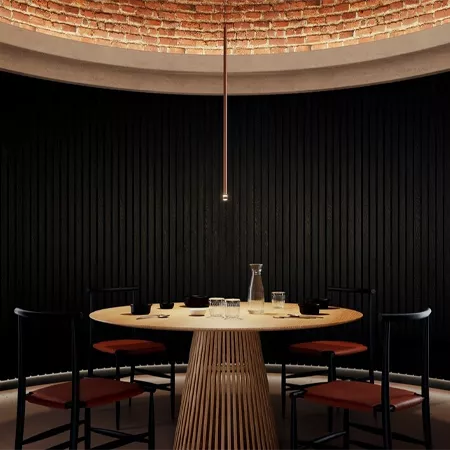 Darc — Une table ronde en bois clair entourée de quatre fauteuils rouges, placée sous un lustre suspendu au centre d’un salon aux murs noirs striés et
