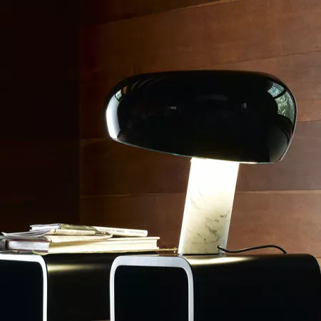 Darc — Une lampe design sur un bureau, composée d'une tablette noire et d'un pied en marbre blanc, éclairant légèrement un espace de travail avec des