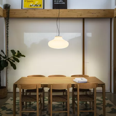 Darc — Une table de réunion en bois clair, entourée de six chaises, éclairée par un luminaire suspendu en forme de dôme. L’espace est minimaliste avec