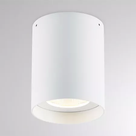 Darc — Applique murale en forme de cylindre blanc, avec une lumière douce et diffuse émise par un rebord circulaire en bas, créant un éclairage ambian