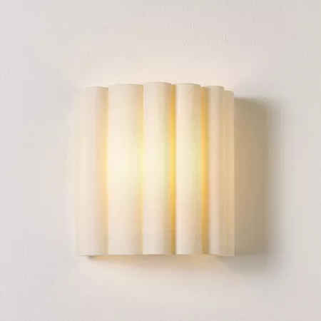 Darc — Applique murale composée de cinq rouleaux beige clair disposés verticalement, émettant une lumière douce et chaude sur un mur blanc.
