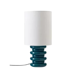 Darc — Lampe design avec un pied en forme de ressorts turquoise et un abat-jour blanc cylindrique, posée sur une surface noire