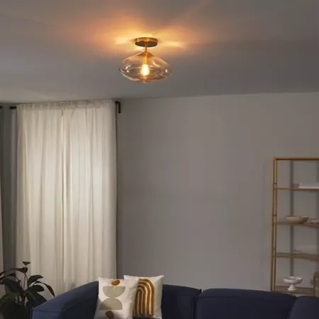 Darc — Un salon spacieux avec un canapé bleu foncé, des coussins blancs et dorés, éclairé par un luminaire suspendu moderne en verre et métal, près d'