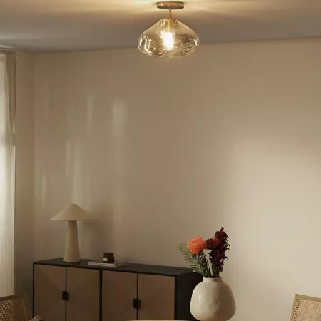 Darc — Une pièce lumineuse avec un plafonnier en verre teinté diffusant une lumière douce, une étagère noire basique posée contre un mur clair, et un